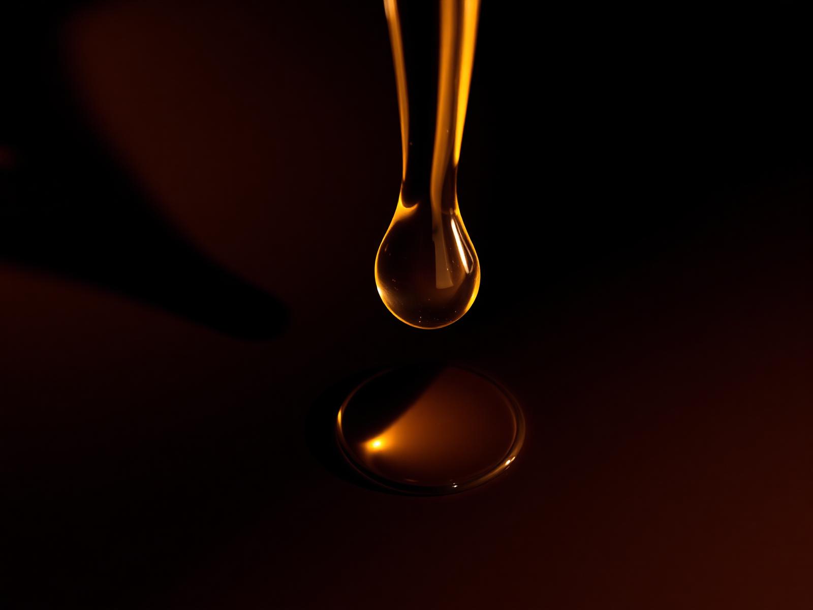 Gota de aceite cayendo sobre superficie oscura — grasa hepática.