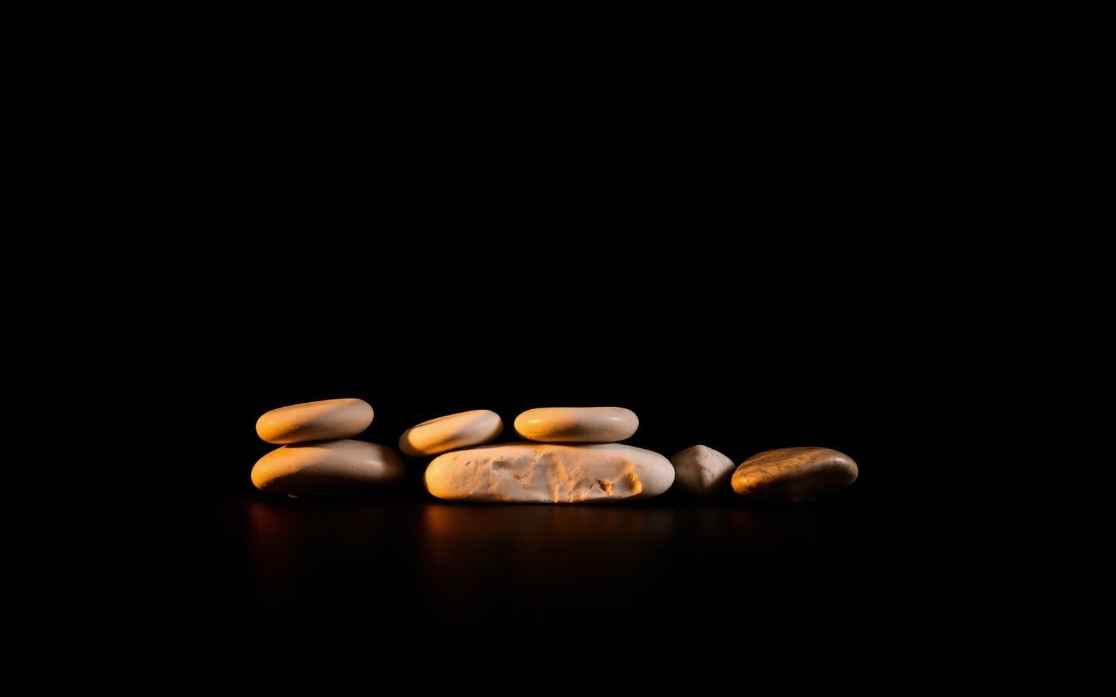 Cinco piedras iluminadas con luz cálida sobre fondo oscuro, imagen editorial sobre los criterios del síndrome metabólico.